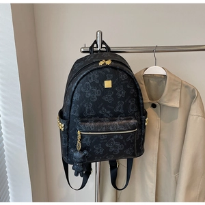 Detail eines schwarzen Rucksacks mit Bärenprint und goldener Metall-Logoplakette