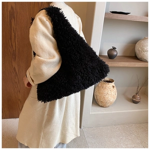 Detail of large black shaggy faux fur tote bag showing texture on woman's shoulder