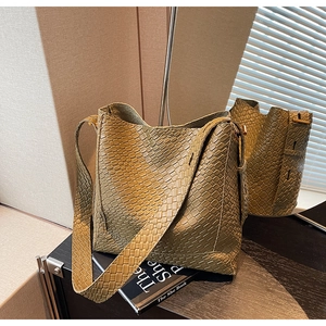 Détail du cuir tressé vert olive d'un sac seau avec une large bandoulière