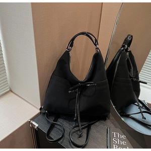 Detail view of the black crescent hobo bag with a decorative bow and glossy handle