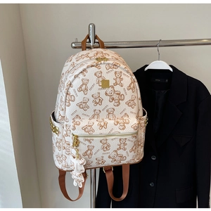 Detail des cremefarbenen Rucksacks mit Teddybär-Prints und goldenen Nietenakzenten