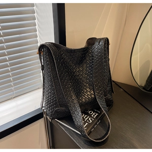 Détail de la texture en cuir tressé noir et de la large bandoulière du sac à main