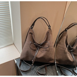 Macro detail of dark brown frosted suede texture and delicate bow on a tote bag