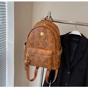 Detail eines braunen Lederrucksacks mit Bärenmuster, Gold-Hardware und Nieten-Elementen