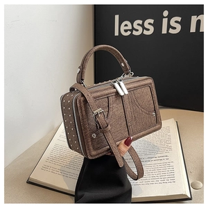 Detail der braunen Vintage-Tasche mit silbernen Nieten und Doppelreißverschluss