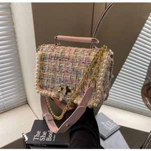Close-up of pink tweed crossbody bag with pearl trim and gold clasp on books