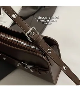 Detail of adjustable leather strap with silver metal buckle and grommets on baguette bag