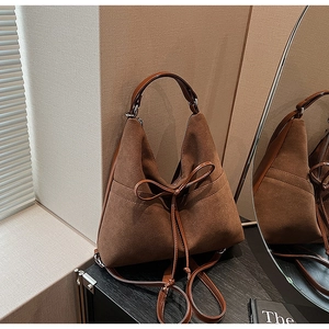 Close-up of deep brown suede tote bag with leather bow detail and textured matte finish