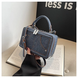 Detail der Denim-Umhängetasche mit braunen Nähten und Metallnieten-Taschendesign