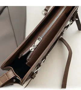 Detailed top view of the smooth silver zipper and stitching on the dark brown leather bag