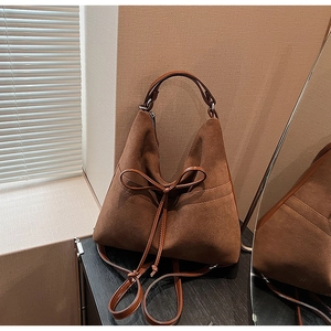 Close-up of brown suede tote bag featuring a leather bow knot and refined stitching