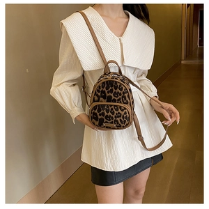 Detail of trendy leopard print mini backpack featuring metal logo and dual zip pockets