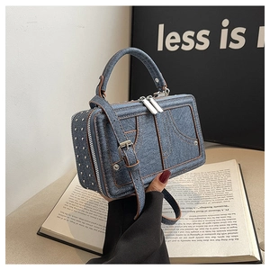 Detailansicht der Denim-Handtasche mit braunem Lederbesatz und silbernen Metallnieten