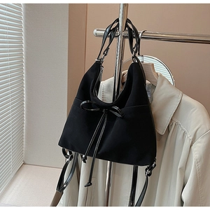 Detail of black frosted tote bag with glossy bow and shoulder strap on metal hanger