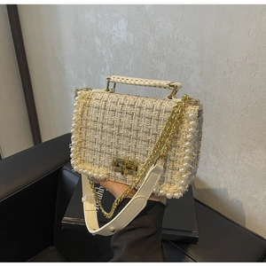 Detail of tweed crossbody bag featuring pearl trim and elegant golden turn-lock closure