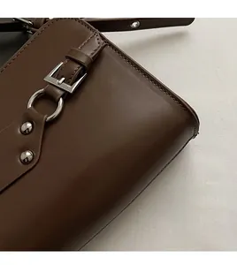 Macro shot of dark brown matte leather bag with silver metal buckle and neat stitching