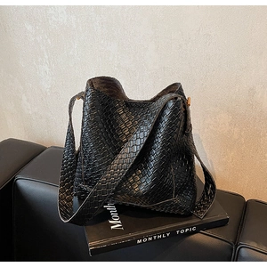 Détail de la texture tressée noire du sac seau rétro avec bandoulière large stylée