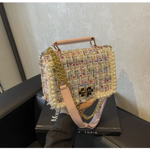 Detail of tweed crossbody bag with pearl trim, leather handle, and gold chain strap