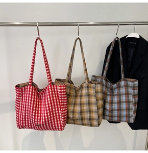 Detailed view of three oversized tweed tote bags with classic checkered patterns and metal logos
