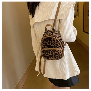 Detailed view of leopard print mini backpack with brown leather trim and metal logo