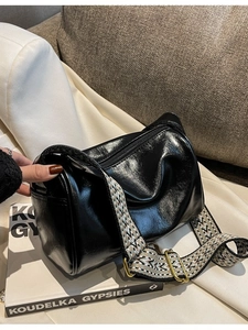 Black glossy boston bag with stylish patterned wide shoulder strap on white fabric