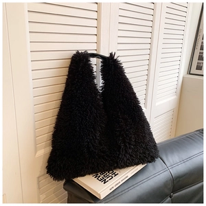 Detail of plush black faux fur tote bag with smooth leather handles on a bench