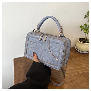 Detailansicht der Denim-Umhängetasche mit Metallnieten und Vintage-Taschennähten