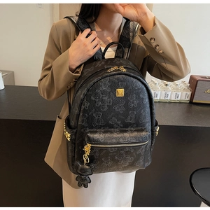 Detail eines schwarzen Rucksacks mit Bärenmuster, goldenen Nieten und Bärenanhänger