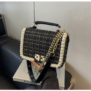 Close-up of black and gold tweed crossbody bag featuring elegant pearl trim and gold hardware