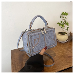 Detail der hellblauen Jeans-Tasche mit Lederbesatz und Metallnieten-Verzierung