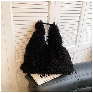 Detail of a black plush faux fur tote bag with smooth handles on minimalist decor