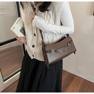 Detail view of dark brown crossbody baguette bag featuring silver buckles and retro straps