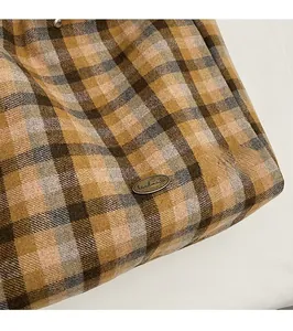 Detailed macro view of the vintage plaid canvas bag with a handmade bronze metal badge