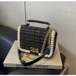 Detail of tweed crossbody bag featuring pearl trim and golden metal turn-lock closure