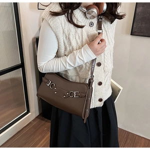 Detail view of dark brown faux leather shoulder bag featuring silver metal buckles and rivets