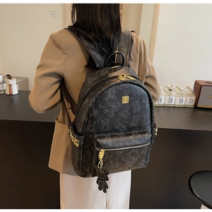 Detailansicht des schwarzen Rucksacks mit Bärenmuster, Goldnieten und Bärenanhänger