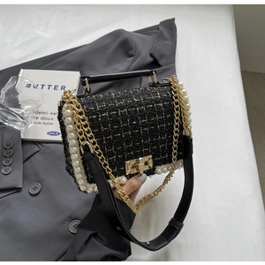 Close-up of black tweed shoulder bag with white pearl trim and gold metal lock