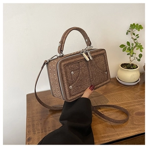 Braune Box-Umhängetasche mit Denim-Textur und Metallnieten in der Hand gehalten