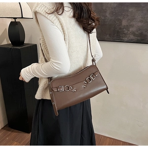 Detail of dark brown leather baguette bag with silver buckles and vintage rivets