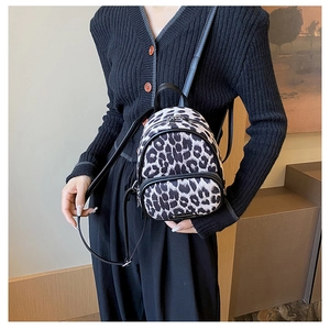 Detail view of mini leopard print backpack with black faux leather straps on a model