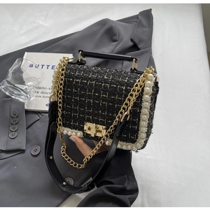 Detail of tweed crossbody bag with pearl trim, gold hardware, and metal chain strap