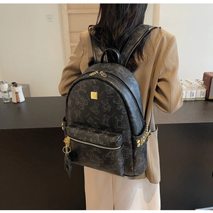 Detail eines schwarzen PU-Lederrucksacks mit Bärenprint, Goldnieten und Metall-Markenplakette