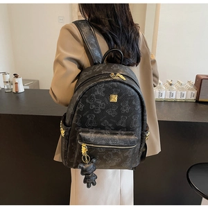 Detail eines Bären-Print Rucksacks mit goldenen Reißverschlüssen und Bärenanhänger