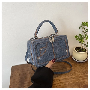 Detailansicht der blauen Denim-Handtasche mit braunen Lederpaspeln und silbernen Nieten