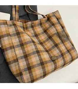Macro detail of plaid fabric texture and handmade metal plaque on the canvas tote bag