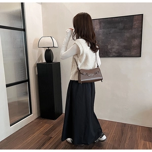 Dark brown leather baguette bag with dual metal buckles shown on model for daily commute