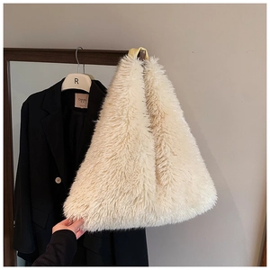 Close-up of off-white faux fur tote bag with leather handle on a black blazer backdrop