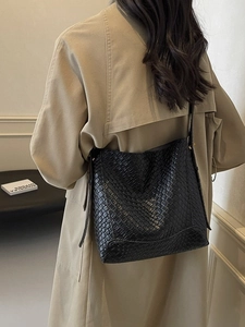 Sac seau vintage noir à motif crocodile porté avec un trench-coat beige élégant