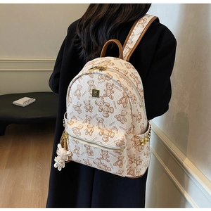 Detail eines cremefarbenen Rucksacks mit Bärenprint, Seitentaschen und Goldnieten