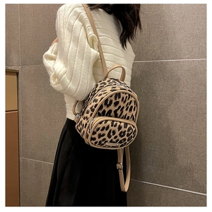 Close-up of leopard print mini backpack with thin brown straps worn by a model